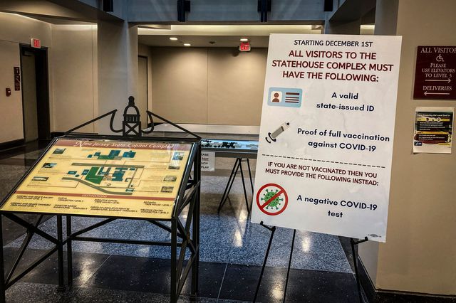 Signs requiring proof of COVID-19 vaccination or a negative test are shown posted outside committee rooms at the New Jersey statehouse in Trenton, December 3rd, 2021